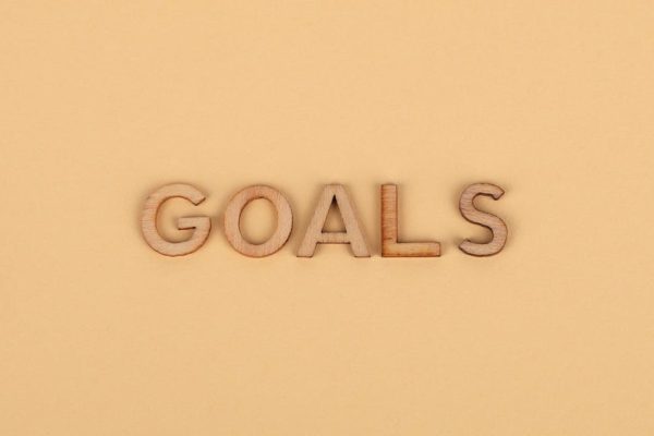 Wooden letters spelling 'GOALS' on a plain background, emphasizing motivation.