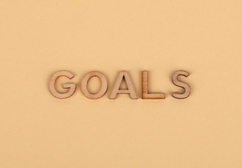 Wooden letters spelling 'GOALS' on a plain background, emphasizing motivation.
